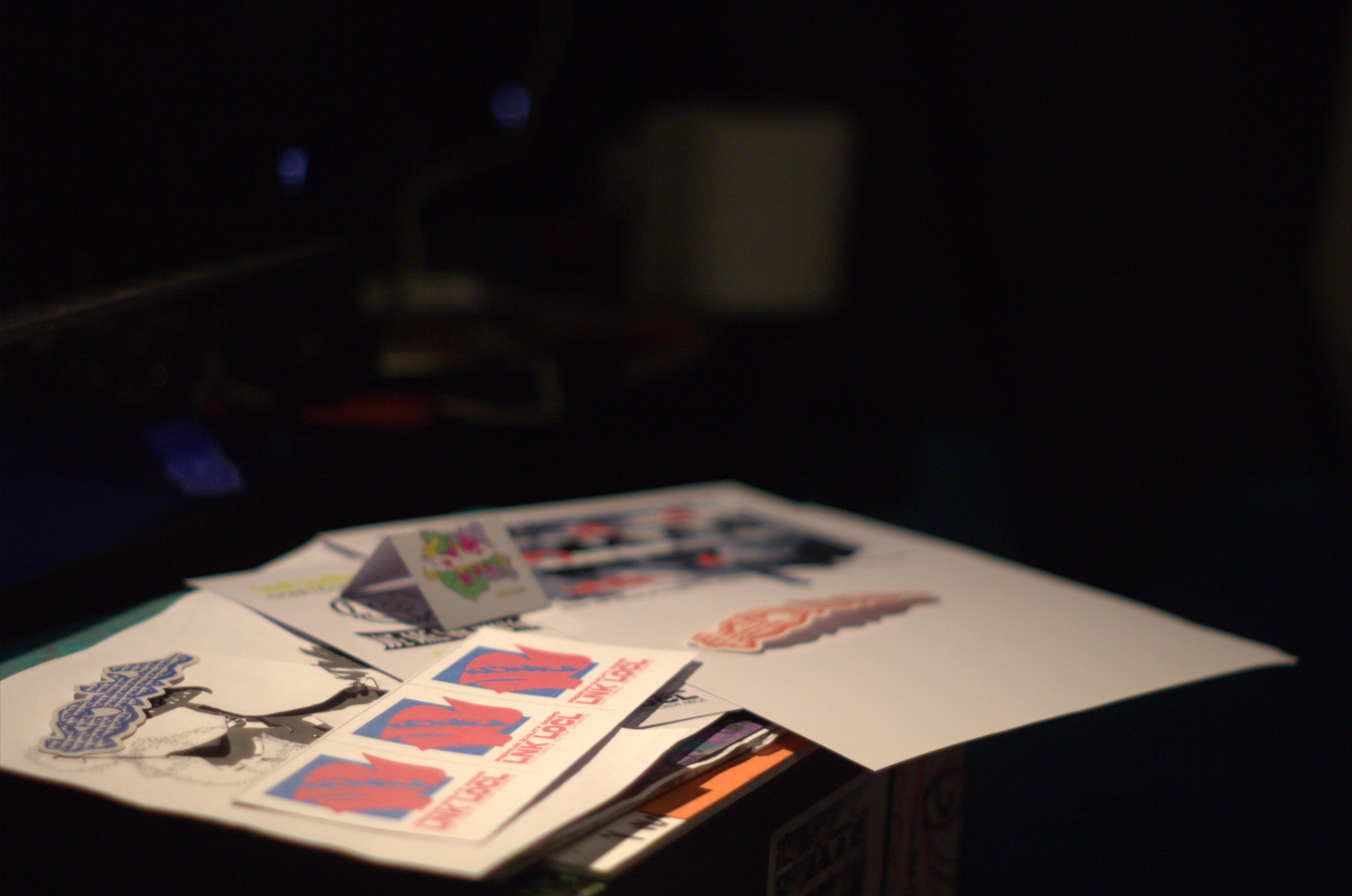 Konka Krew printed artwork and stickers spread on a dark table