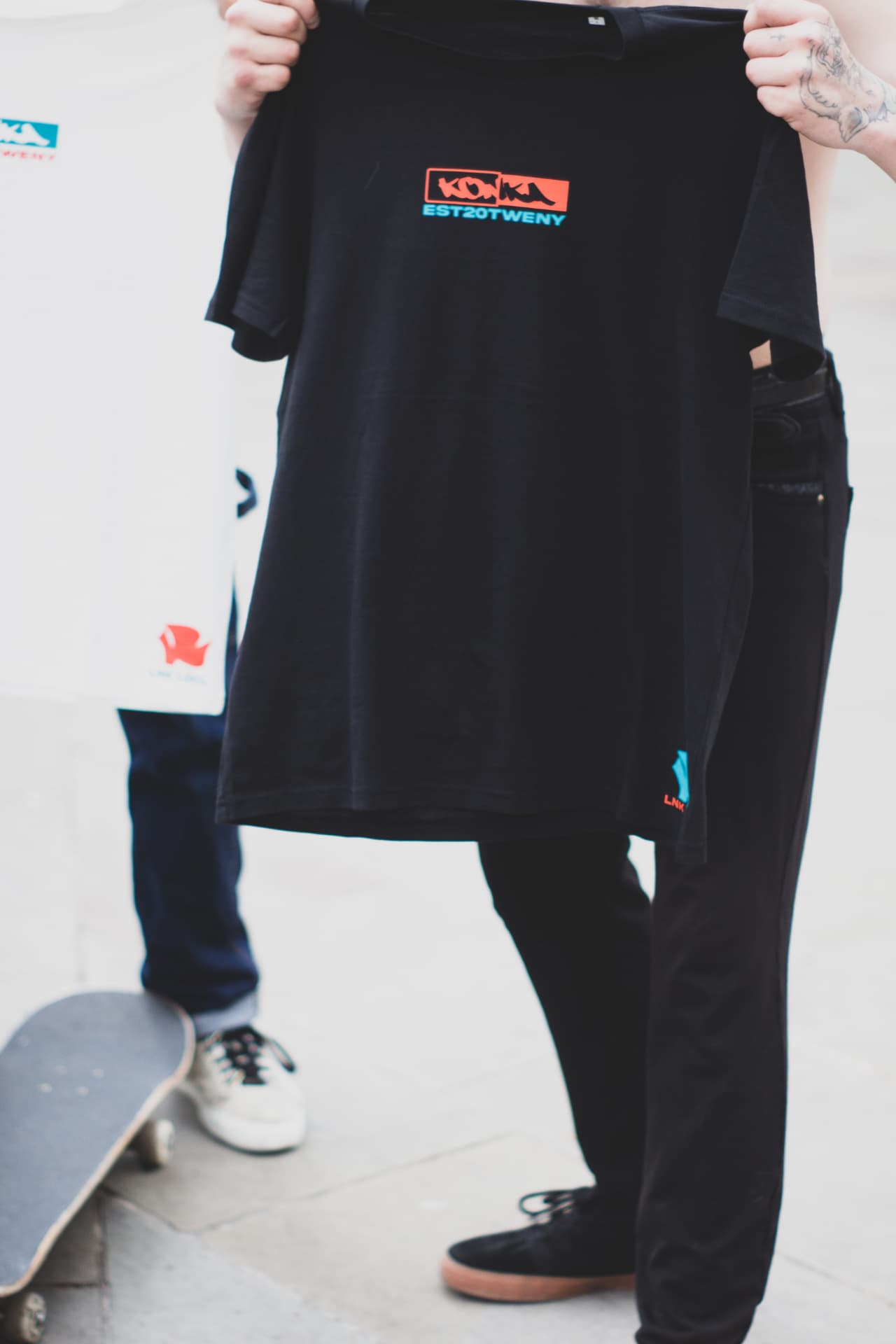 Two friends on concrete steps wearing Konka Krew tees and cargos
